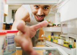 мужчина тянет руку в холодильник